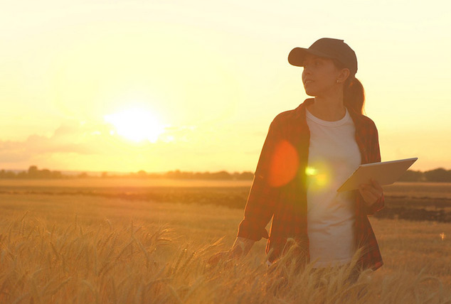 Close up shot of a woman with an exam pad surveying a farm.