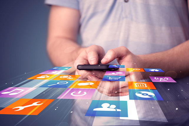 Close up shot of a man using his cellphone with widget icons floating out of it.