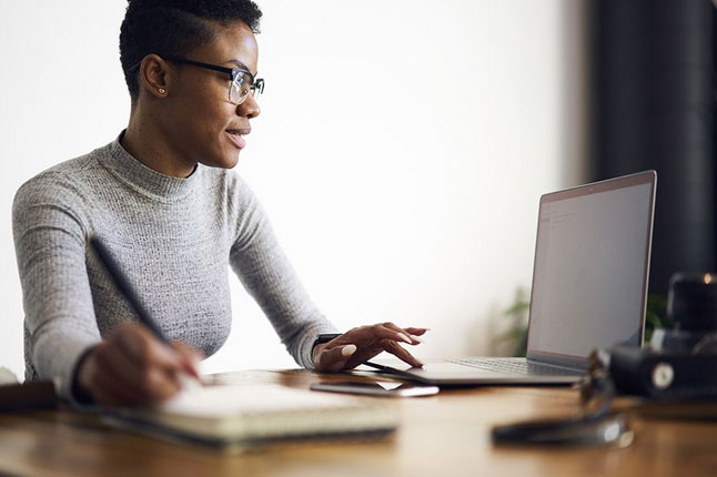 Software developer looking at a laptop with her finger on the trackpad.