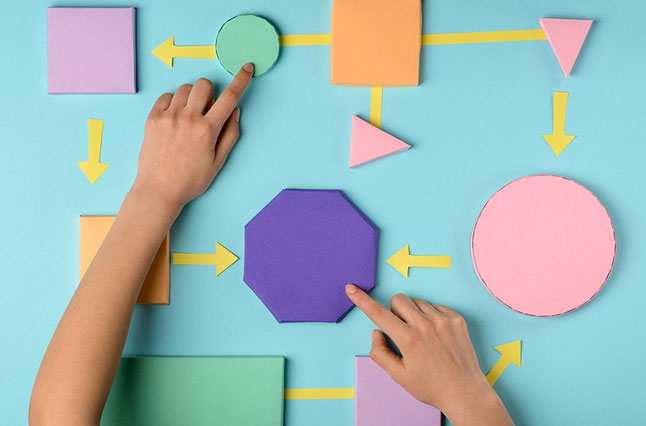 A pair of hands rearranging multicoloured shapes on a blue background.