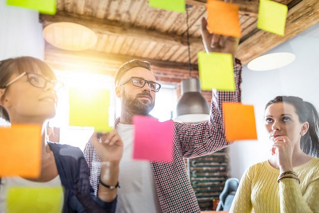 A group of employees analysing sticky notes hanging from the ceiling.