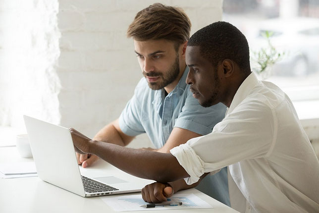 Two employees discussing something as they look at a laptop screen.