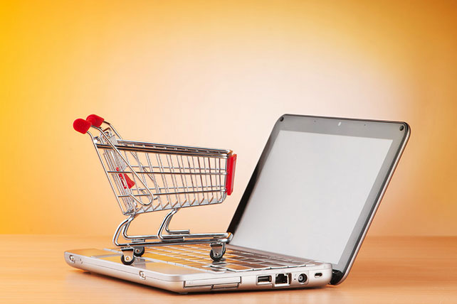 Image of an open laptop with a miniature shopping cart placed on the keypad.