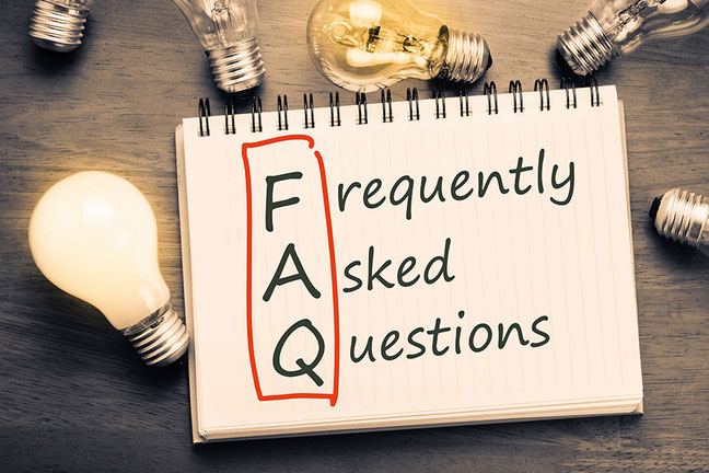 Wooden table with light bulbs and a sheet of paper with the words 'Frequently Asked Questions' written in red and black.