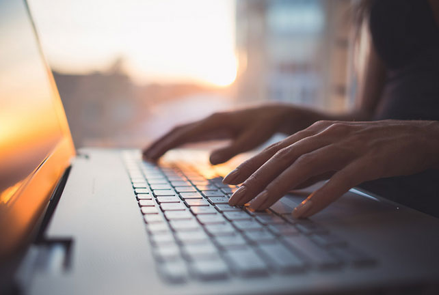 Close up of a pair of hands typing on a laptop.