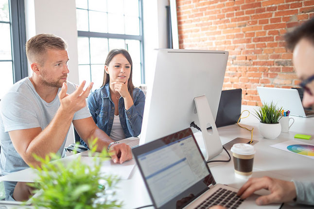 A team of software developers brainstorming while they look at a screen.