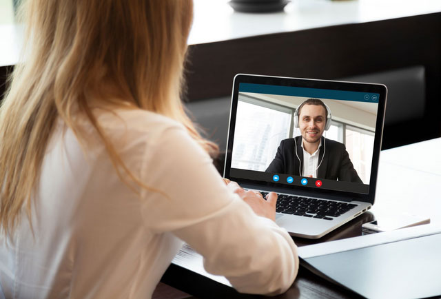 Two employees talking to each other via their laptop's video chat function.